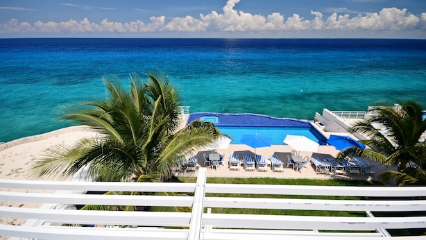 A pool area with lounge chairs and a view of the ocean. - Delightful Oceanfront 3BR Condo South tower,the best Ocean views in the complex! (Cozumel)