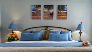 Ein Bett mit blauer Bettwäsche, einem hölzernen Kopfteil und einer Blumenkomposition.