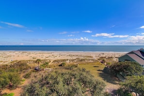 Vista de la playa con una casa y cielo despejado.