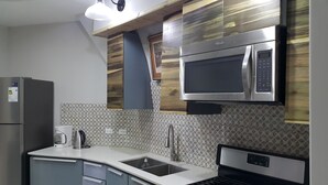 Una cocina moderna con microondas integrado, refrigerador de acero inoxidable y cafetera.