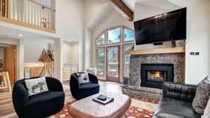 A spacious living room with a fireplace, comfortable seating, and a large TV.
