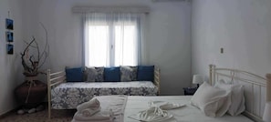 Cozy retreat with two beds, a large window, and a decorative vase.