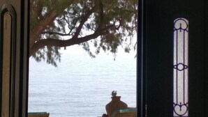 Une vue à travers une fenêtre donnant sur une étendue d’eau, un arbre et une chaise.
