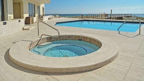 A swimming pool with a hot tub, a deck area, and a view of the ocean. - Coastal Castle. 4 Bedroom Gulf Front condo. (Navarre Beach)