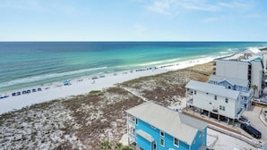A beachside hotel with a view of the ocean, a sandy beach, and a clear sky. - Coastal Castle. 4 Bedroom Gulf Front condo. (Navarre Beach)