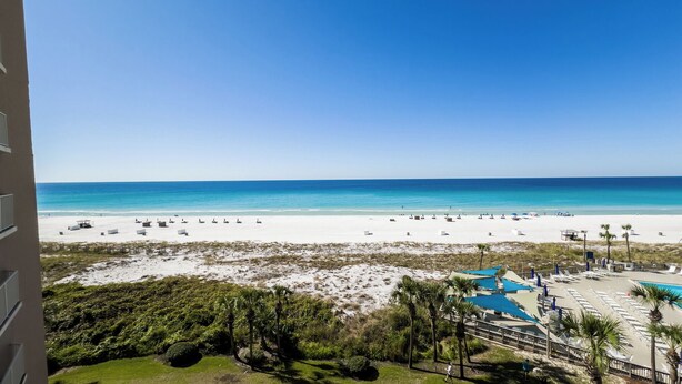 A beach view from a balcony with a pool area and palm trees. - E604 Amazing Gulf View, 3 Pools, 2 FREE Beach Chairs! (Panama City Beach)