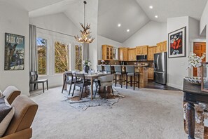 A spacious kitchen with modern appliances, a dining area with a large table and chairs, and a cozy living room with a fireplace.