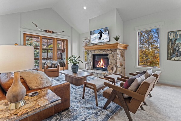 A spacious living room with a fireplace, comfortable seating, and a large window with a view.