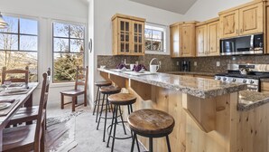Eine Küche mit Holzschränken, einer Granit-Arbeitsplatte und einer großen Kochinsel mit Sitzgelegenheiten.