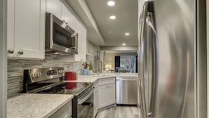 Una cocina moderna con electrodomésticos de acero inoxidable, armarios blancos y salpicadero de azulejos.