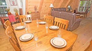 Comedor con mesa de madera dispuesta para seis personas, rodeado de sillas de madera.