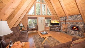 Un acogedor loft con chimenea de piedra, vigas de madera, un sofá de cuero y un televisor.