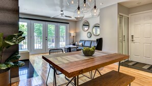 A modern living room with a dining table, a sofa, and a ceiling fan. - Modern Montreal Village Condo – Chic Design, Prime Location, Incredible Style! (Centre-Sud South)