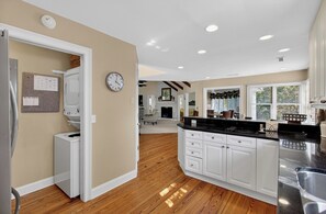 Una cocina amplia con armarios blancos, piso de madera y un ventanal que proporciona luz natural.