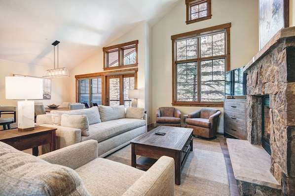 A spacious living room with a fireplace, large windows, and a cozy seating area.
