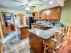 A kitchen with wooden cabinets, a central island, and a stone tile floor.