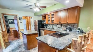 A kitchen with wooden cabinets, a central island with a sink, and a built-in stove.