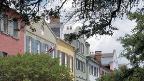 A row of colorful buildings with distinct architectural styles, including a yellow building with a white roof and a pink building with blue shutters. - 12 42nd Avenue by AvantStay | 2 Mins To The Beach | Screened In Porch! (Isle of Palms)