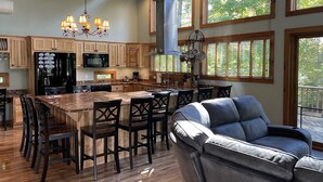 A spacious kitchen with wooden cabinets, a large island, and a dining area with chairs. - Beautiful Home, Views, Near Whiteface, Lake Placid (Wilmington)