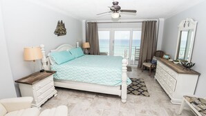 A bedroom with a bed, dresser, nightstand, and a ceiling fan.