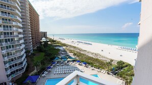 A hotel with a pool, beach view, and multiple balconies.