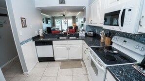 A modern kitchen with white cabinets, a black countertop, and a Samsung microwave.
