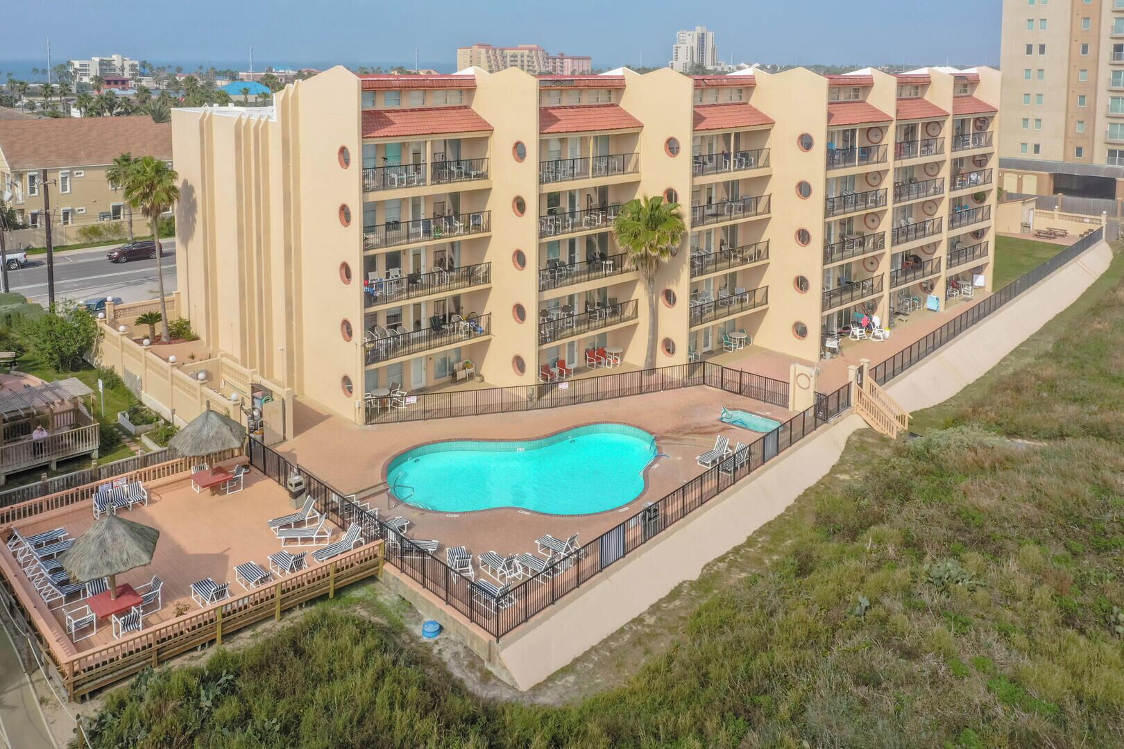 Un hôtel à plusieurs étages doté d’une piscine sur le toit, d’un espace extérieur aménagé et de balcons.