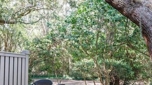 Une terrasse extérieure avec une table et des chaises, entourée d’arbres et de verdure.