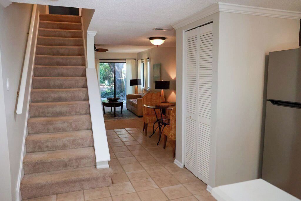 A staircase leading to a dining area with a table and chairs, a refrigerator, and a sliding door.