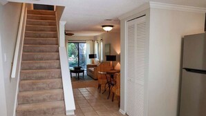 Un escalier menant à un coin repas équipé d’une table et de chaises, d’un réfrigérateur et d’une porte coulissante.