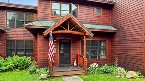 Ein zweistöckiges Holzhaus mit Veranda, einer amerikanischen Flagge und einem Briefkasten.