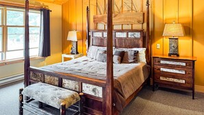 Ein Himmelbett mit Holz-Kopfteil, eine Bank am Fußende und ein Nachttisch mit Lampe.