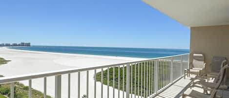 A balcony with a view of a beach and ocean.
