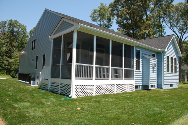 A two-story house with a covered porch and a fenced yard. - Spacious 5BR House, 2 pools & pickle ball, bike to beach, linen provided (Rehoboth Beach)