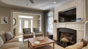 A living room with a fireplace, two armchairs, a sofa, and a coffee table. - 73 Grand Pavilion by AvantStay | Corner Lot, Porch (Isle Of Palms)