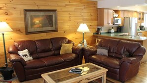 A cozy living room with two leather sofas, a glass coffee table, and a wooden floor. - Townhome B4 - 4th Lake (Inlet)
