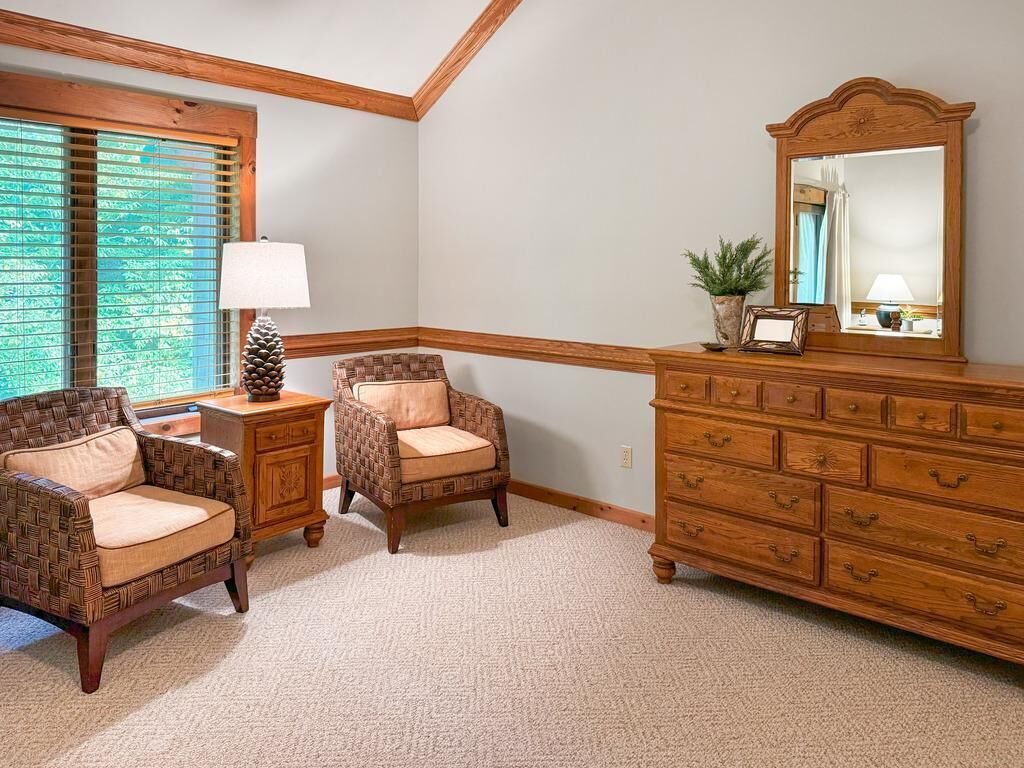 Ein Schlafzimmer mit zwei Korbstühlen, einer Holzkommode und einem großen Spiegel.