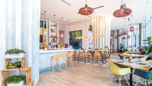 A modern restaurant with a bar area, wooden flooring, and multiple seating options including bar stools and tables. - 38th-floor beachfront residence with panoramic ocean & city views (Hollywood Beach)