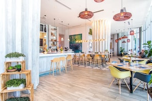 Un restaurant modern amb zona de bar, sòl de fusta i diverses opcions de seients, incloent tamboretes i taules.