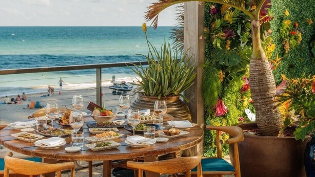 A dining table set with plates, glasses, and a potted plant. - 38th-floor beachfront residence with panoramic ocean & city views (Hollywood Beach)