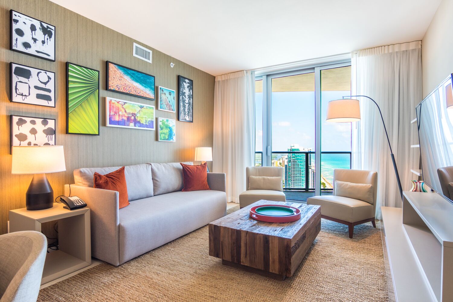 Une chambre d’hôtel moderne, dotée d’un canapé, de fauteuils, d’une table basse et d’œuvres d’art accrochées aux murs.