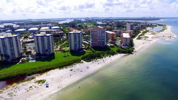 A coastal area with high-rise buildings, a beach, and a marina.