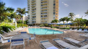 A pool area with lounge chairs and a building in the background.