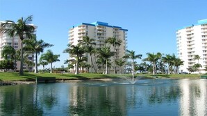 A waterfront hotel with multiple high-rise buildings, palm trees, and a fountain.
