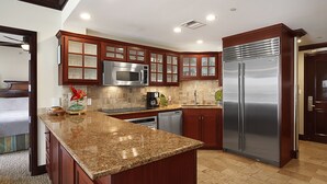 A modern kitchen with granite countertops, stainless steel appliances, and wooden cabinetry. - Waipouli Beach Resort Exquisite Ocean View Condo with Beach Front View (Kapaa)