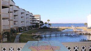 Un hotel sulla spiaggia con numerosi balconi, un molo e un cartello con la scritta 'Pensacola Beach'.