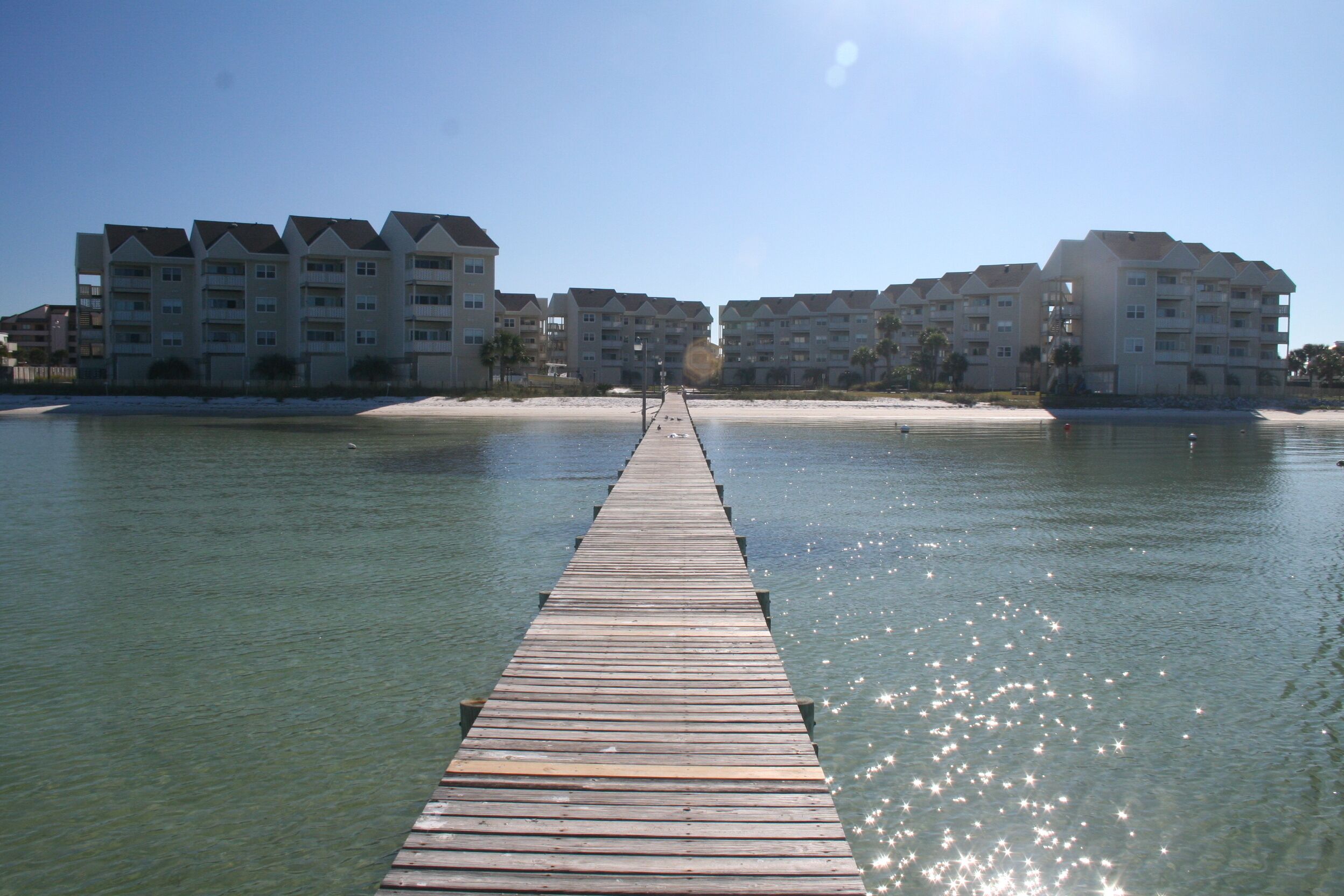 A wooden pier extending into calm waters with clear skies.