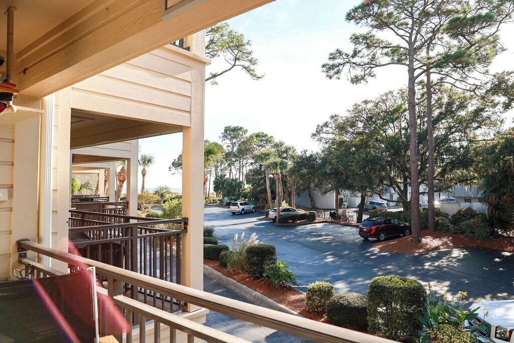 A balcony with a view of a parking lot and surrounding trees.
