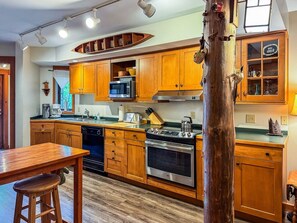 A kitchen with wooden cabinets, a microwave, a stove, and a sink. - Townhome F4 - Vacation Rental on 4th Lake (Inlet)