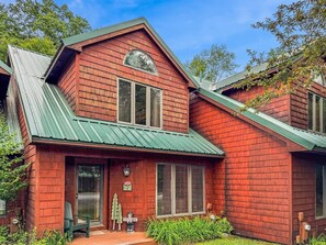 A two-story wooden house with a green roof, a front porch, and a mailbox. - Townhome F4 - Vacation Rental on 4th Lake (Inlet)